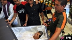 HAB100. LA HABANA (CUBA), 23/07/2012.- Reinaldo Payá (c), hijo del fallecido opositor Oswaldo Payá, observa los restos de su padre hoy, lunes 23 de julio de 2012, en una iglesia de La Habana (Cuba). Unas 400 personas recibieron hoy los restos mortales de