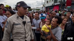 Un hombre con un niño en brazos grita consignas a un miembro de la Policía Nacional Bolivariana (PNB) hoy, martes 14 de junio de 2016, durante una protesta para exigir alimentos en el sector popular Catia, en Caracas (Venezuela). Nuevos focos de protesta